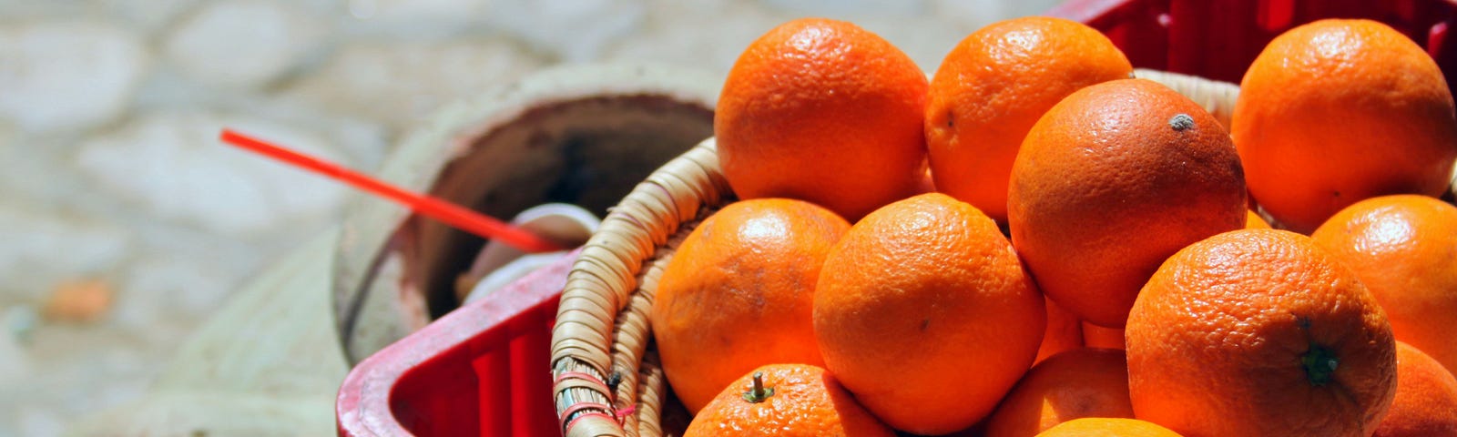 basket of oranges on top of a red plastic crate