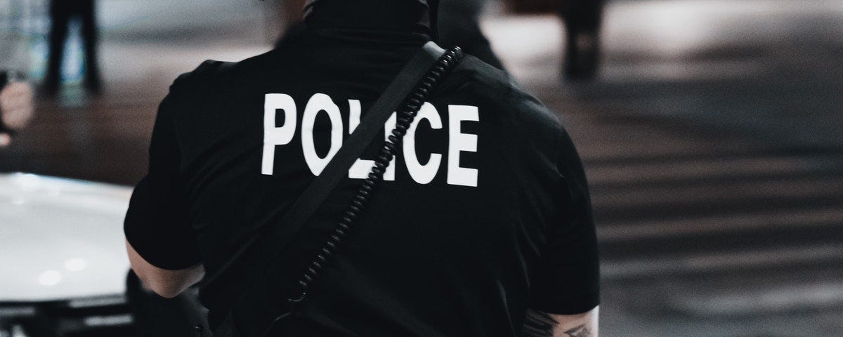 policeman facing away from the camera on a city street in the evening