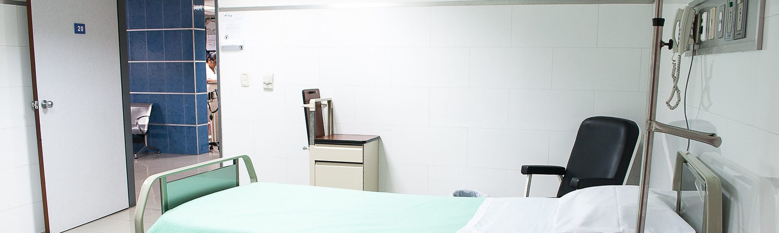 A clean hospital bed is in a hospital room.