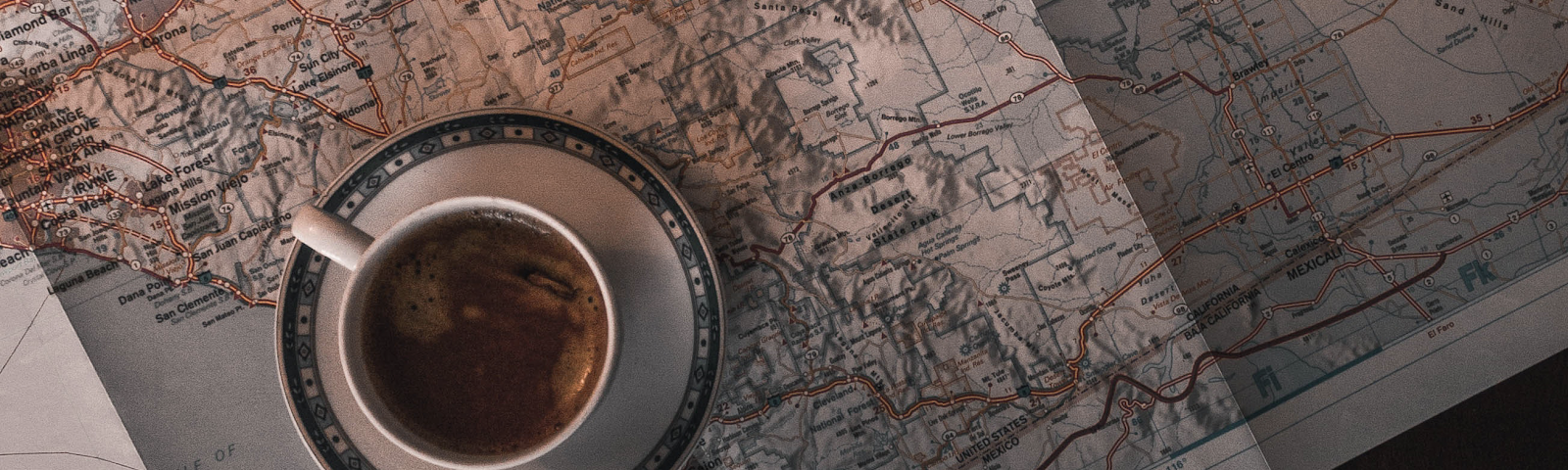 A cup of coffee sitting on a saucer that is sitting on a highway map