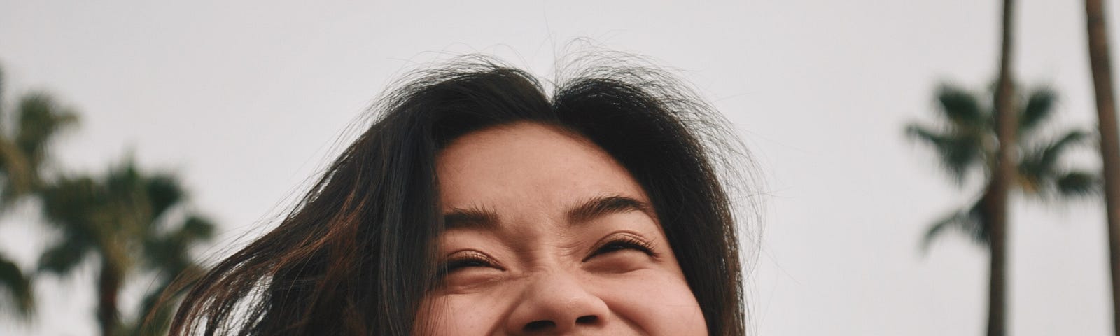 A young woman’s smile lightens up an avenue of palm trees.