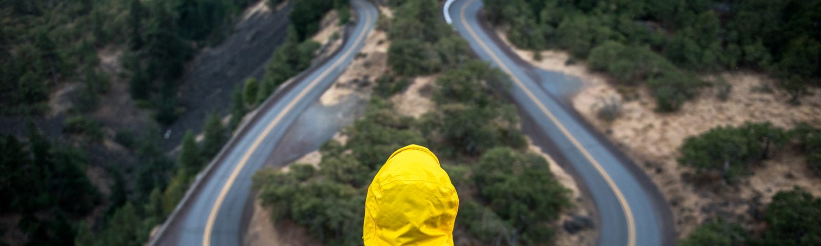 Woman in a yellow rain slicker staring at a wet black crossroads, a fork in the road. She has a choice to make.