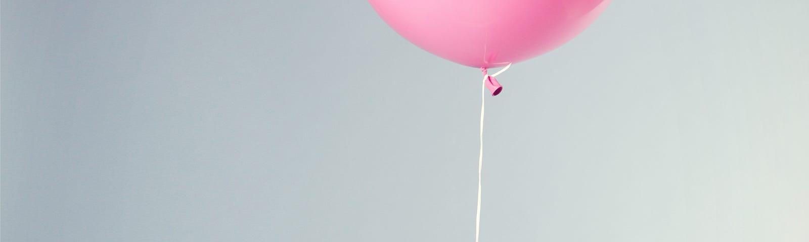 a pink balloon tied to a white chair