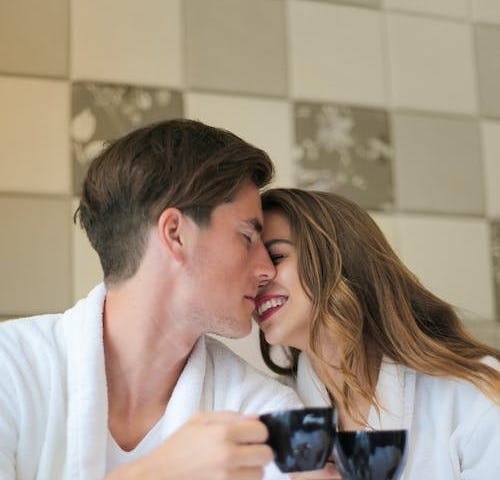 A cuddly couple, nuzzling while enjoying coffee together.