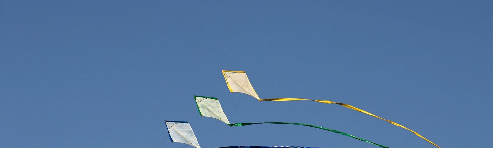 Three kites in a clear blue sky