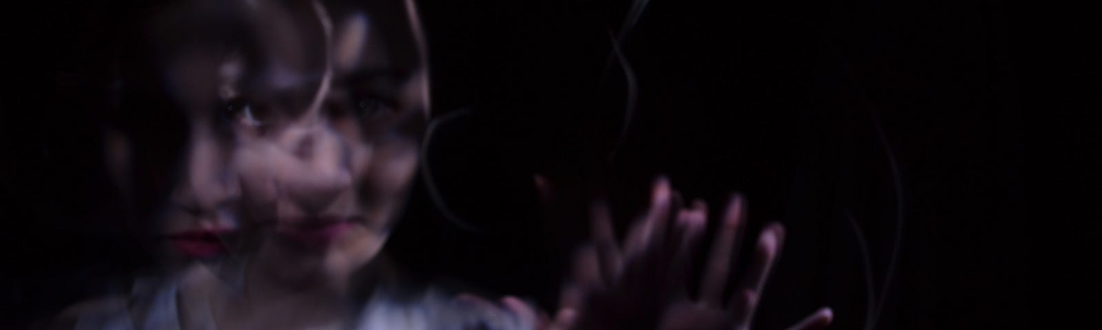 A darker image of a woman, where the woman is not in focus, and stretching out her hands, to go with the story about a man in a motel, and something under the bed kept him awake.