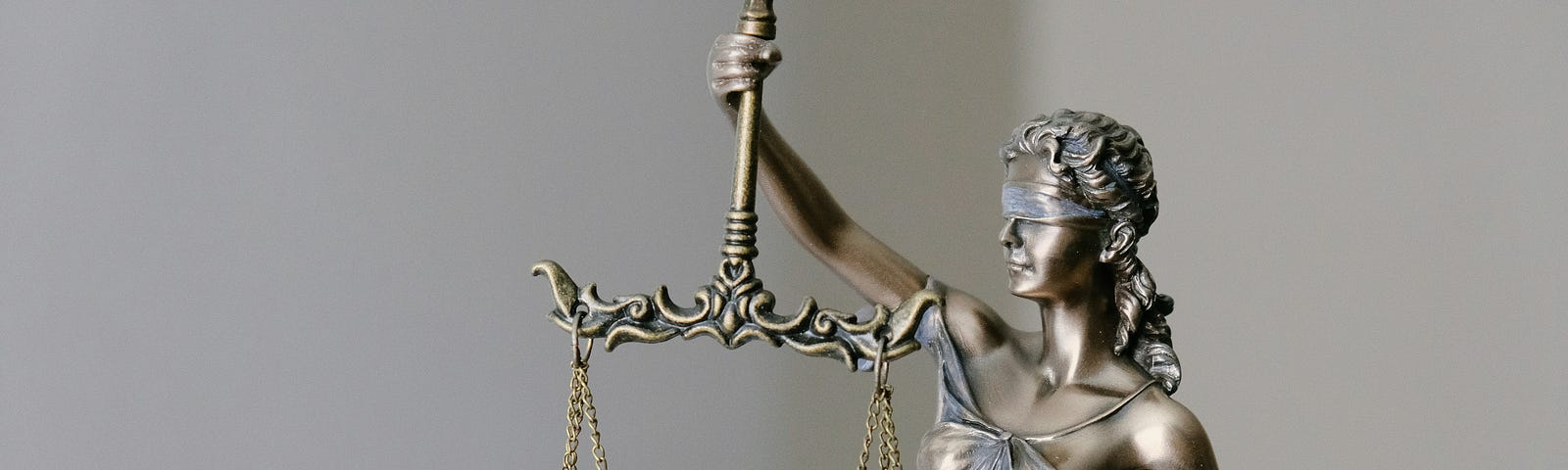 A bronze sculpture of Lady Justice, blindfolded eyes with a balance & a sword in hands.
