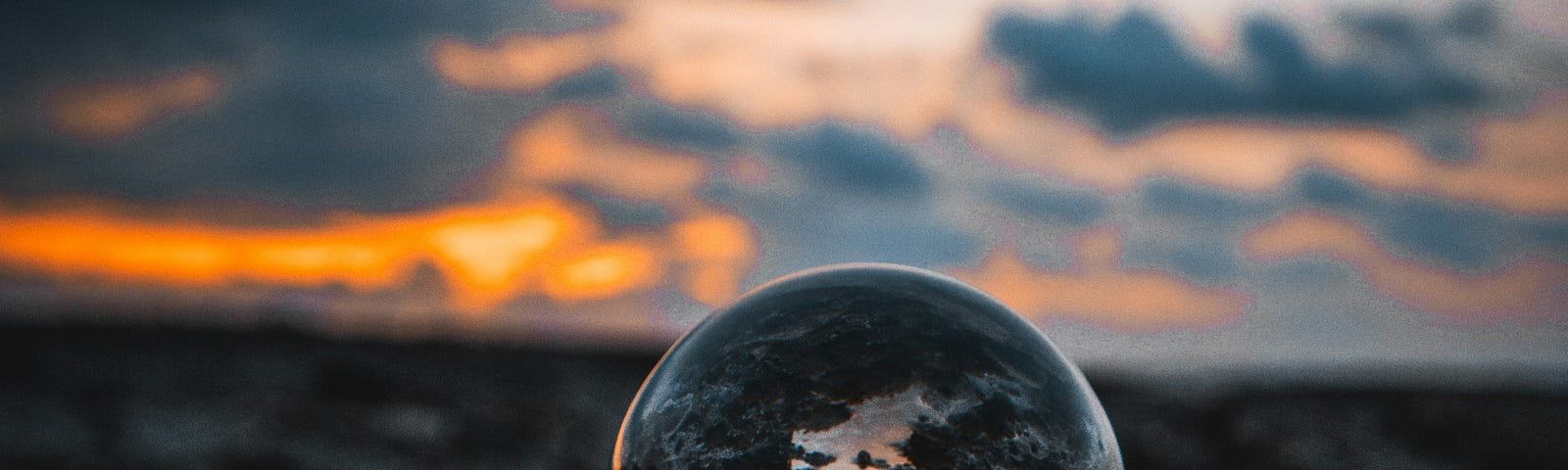 A crystal ball over a landscape during a sunset