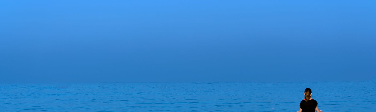 Someone meditating on a beach.