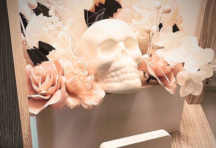 Photo of a white plastic skull nestled in pink flowers, which were Halloween decorations in the author’s therapy office.