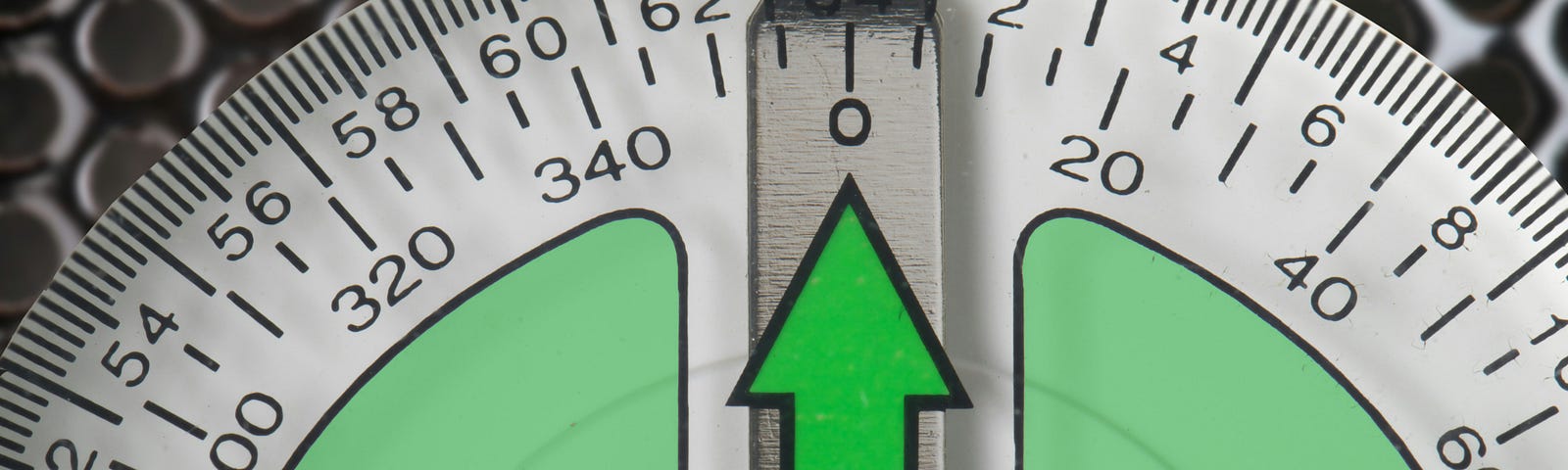 A measurement dial marked with two different scales. A green arrow points to 64/0.