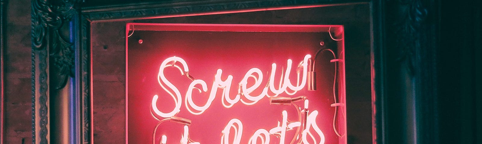 Neon sign with the words “Screw it, let’s do it” emblazoned in red.