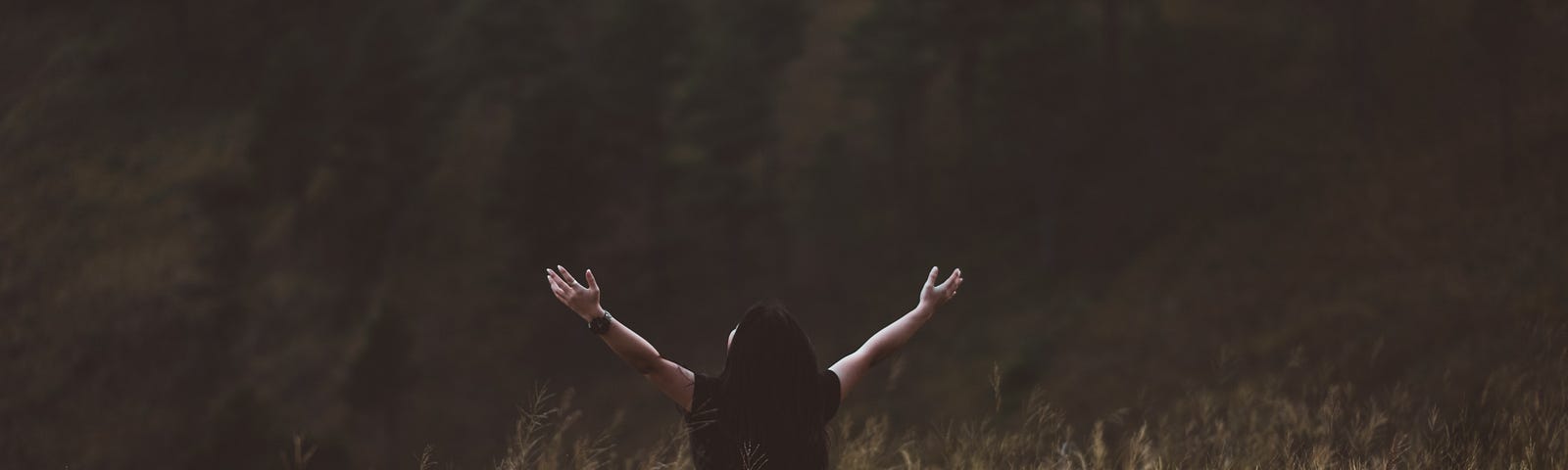 Woman standing in a field with her hands outstretched in worship to God