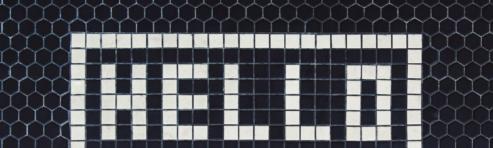 dark mosaic tile floor that spells the word HELLO in lighter color tile