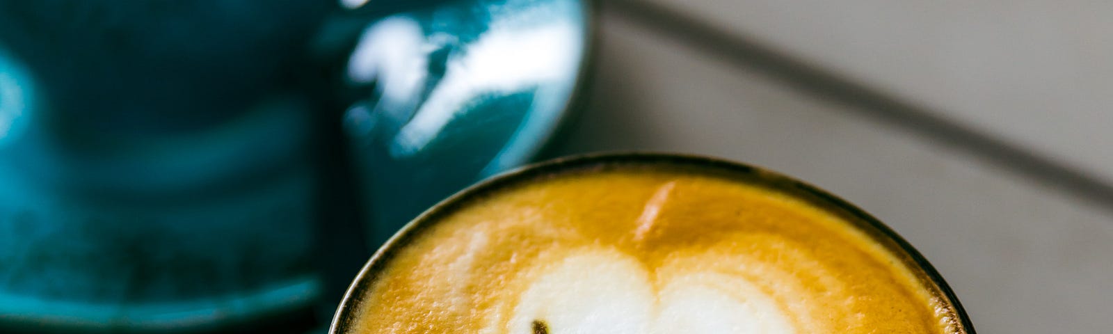 Creamy coffee frothing in blue cups on blue saucers, saying “Yeah!”