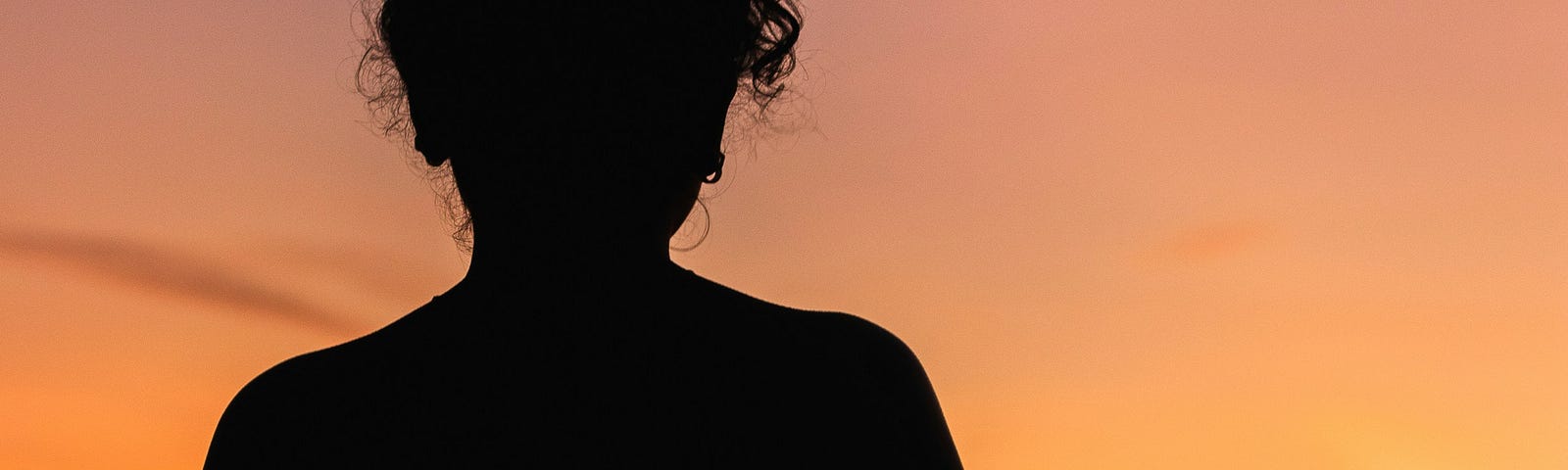 A woman silhouetted against an orange sky