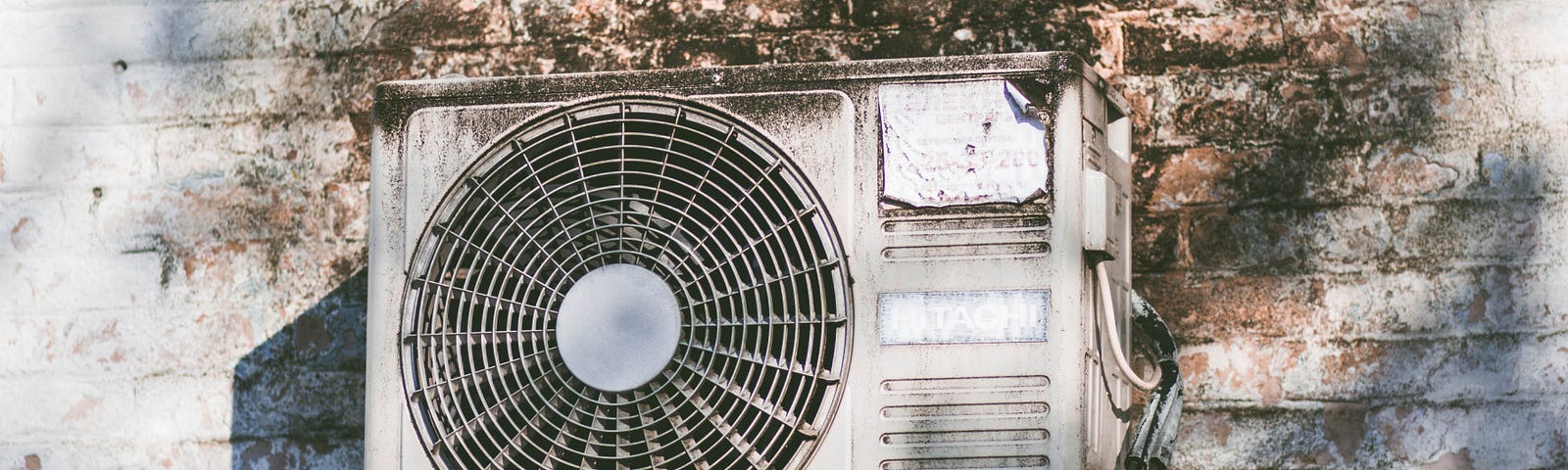 An old air conditioner coming out of a dirty wall