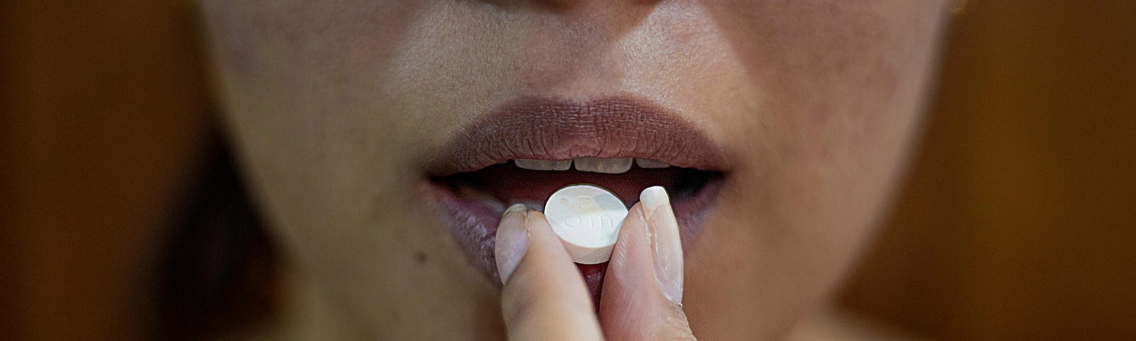 A woman placing a pill in her mouth.