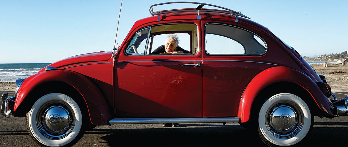 Woman smiling and leaning into the window of a vintage Volkswagen beetle.