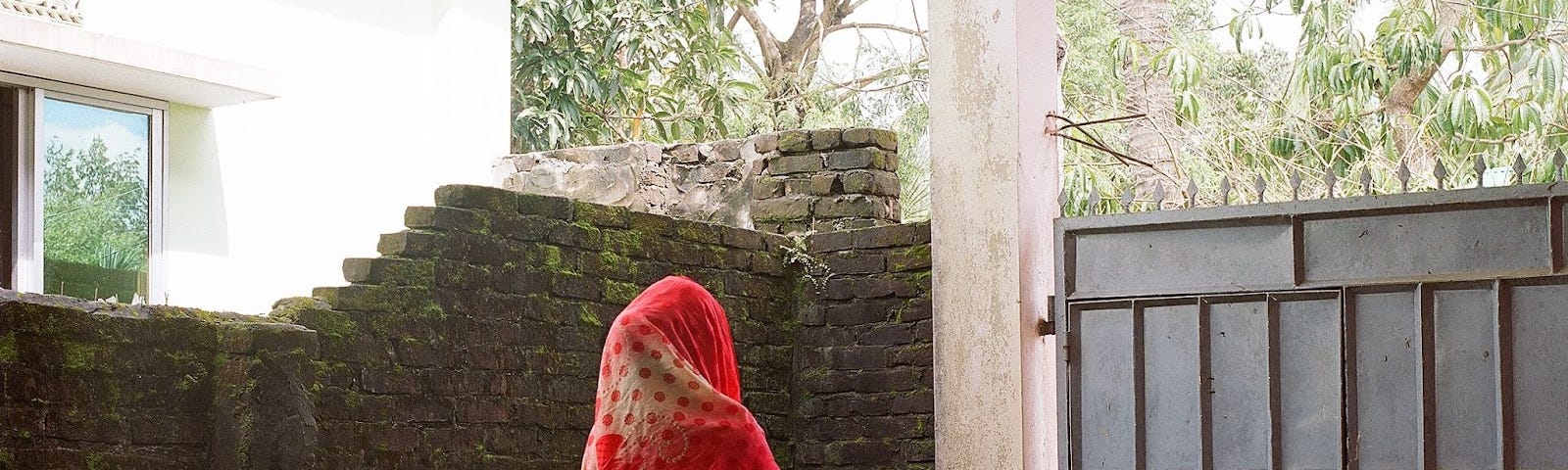 An image of a woman looking past her gates from where she lives