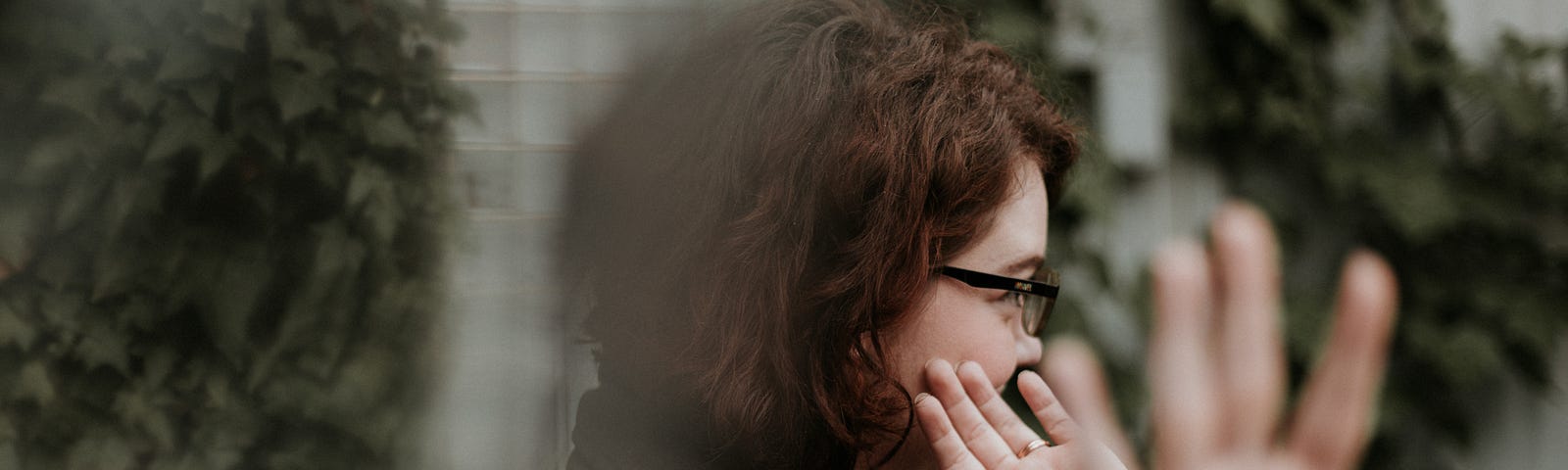 A woman holding her hands up to hide her face from the camera