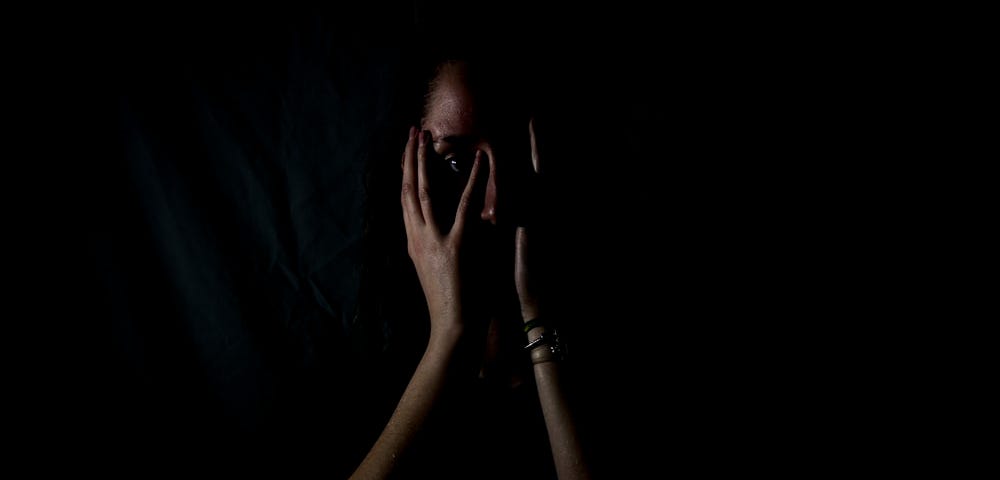 A woman holding her face in a dark room