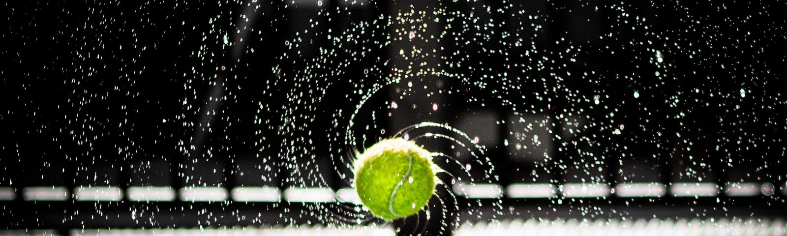 Spinning tennis ball, with spirals of water emanating from it.