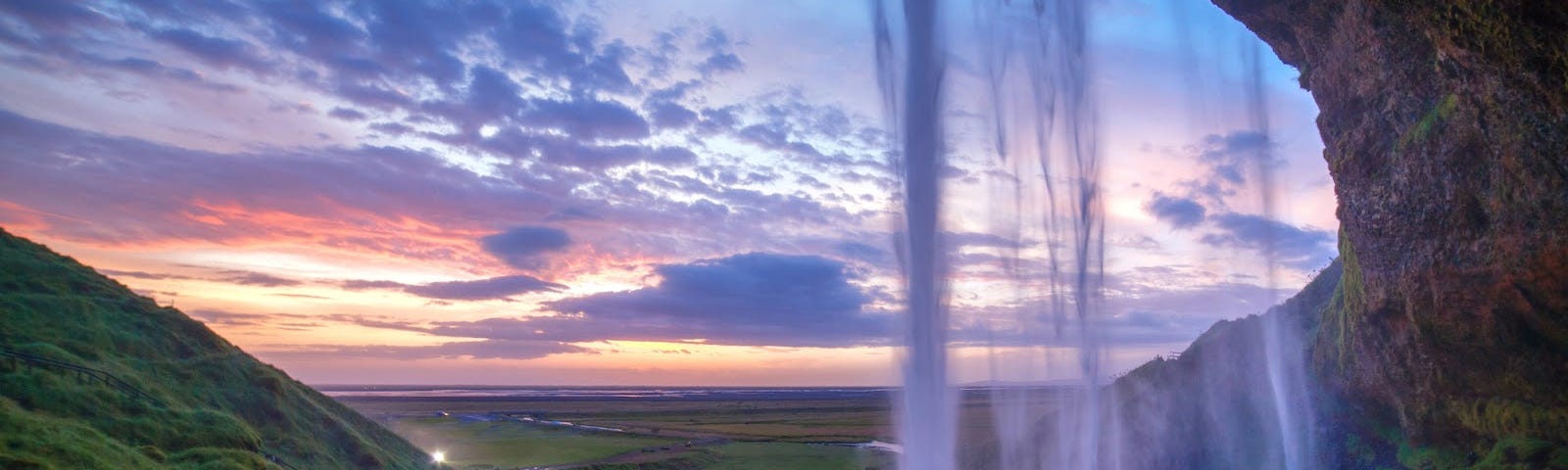 A gorgeous waterfall tumbles down. There is a beautiful sunset in the background.