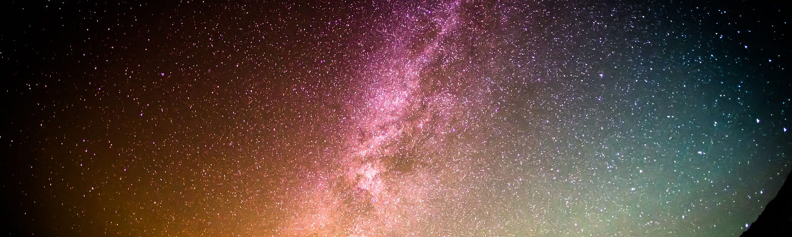 A person stands on the edge of the world, as a golden, pink and silvery universe spreads its infinite stars before him.