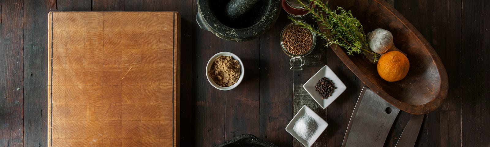 Cooking implements — cutting board, cast iron pan, knives, herbs, mortar and pestle