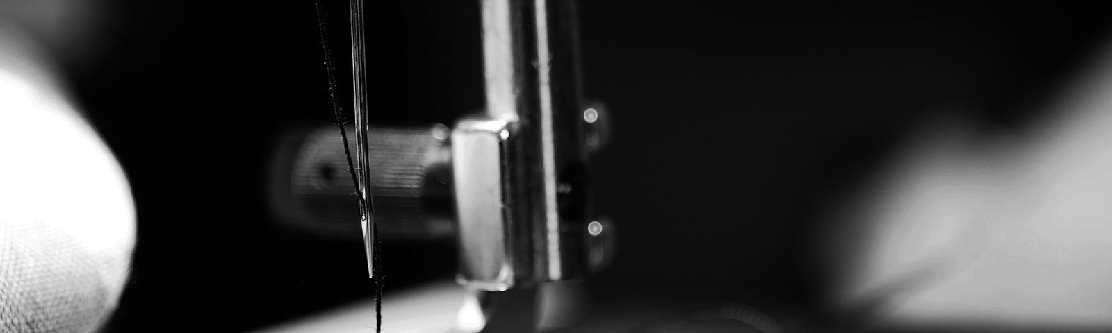 A sewing machine that sews a piece of fabric. Picture in black and white.