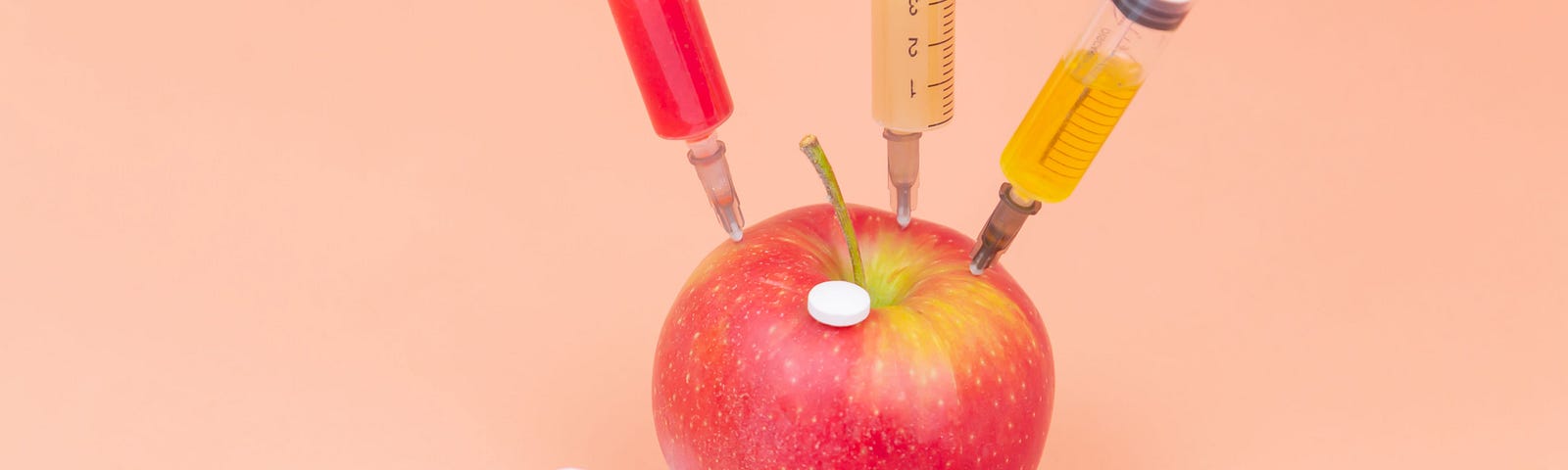 Picture an apple being manipulated with several chemicals using syringes.