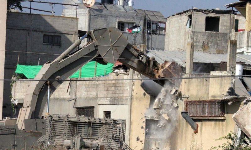 Una excavadora militar israelí destruye una casa palestina en Cisjordania.