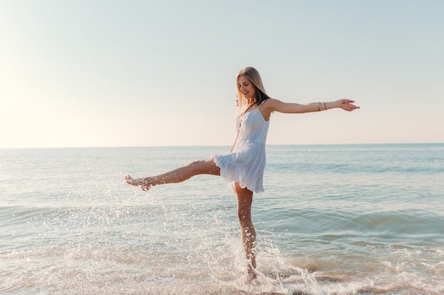 Young, happy woman dancing by the sea shore
