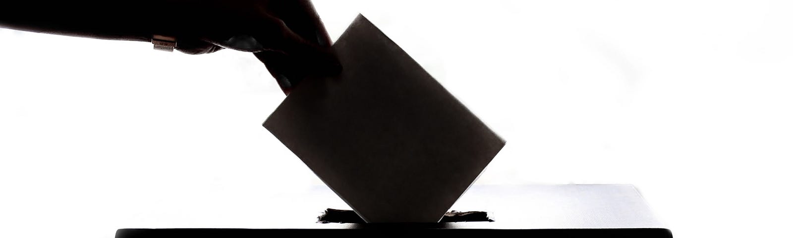 Silhouette of a voter posting their ballot in a ballot box