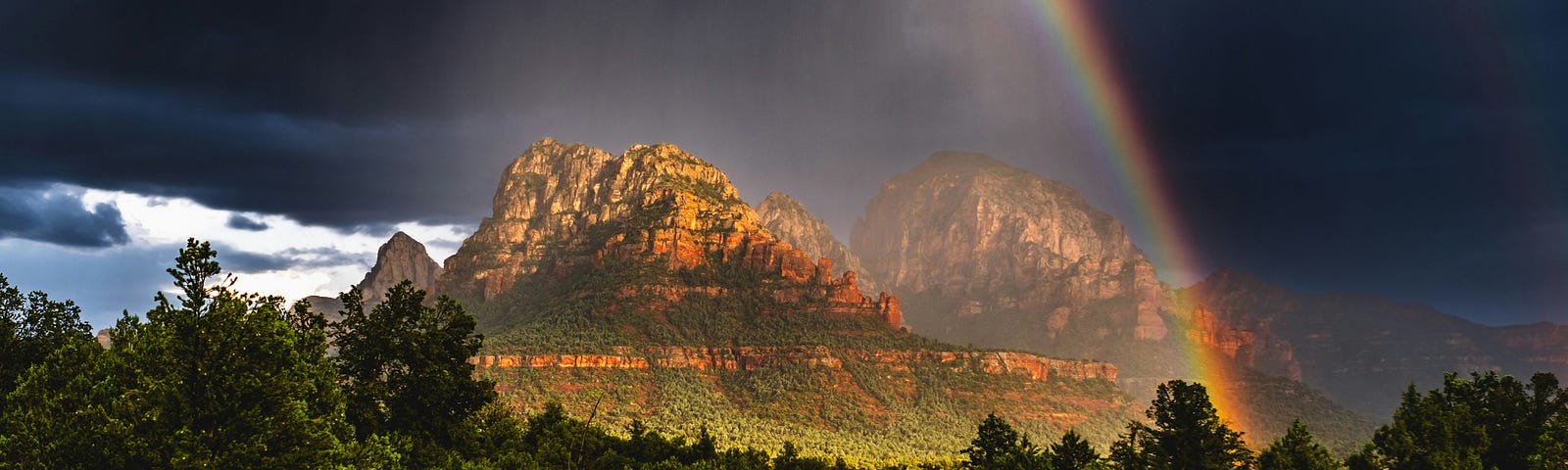 A rainbow surrounds a view of the red rocks in Sedona, AZ.