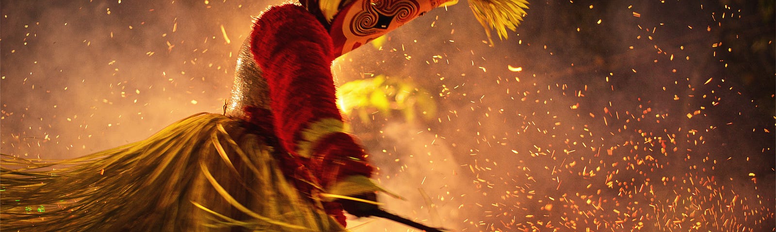 A dancer waves a scythe wearing a headress and grass skirt, surrounded by sparkling grains of light