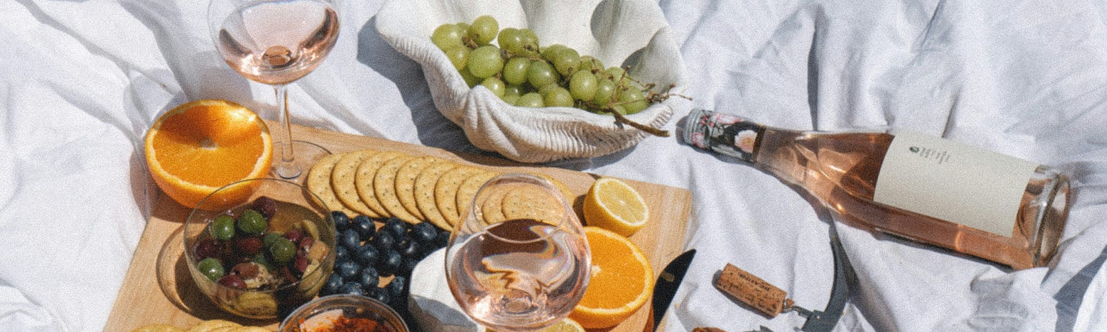 A picnic. Wine, grapes, orange, baguette, crackers, cheese, olives
