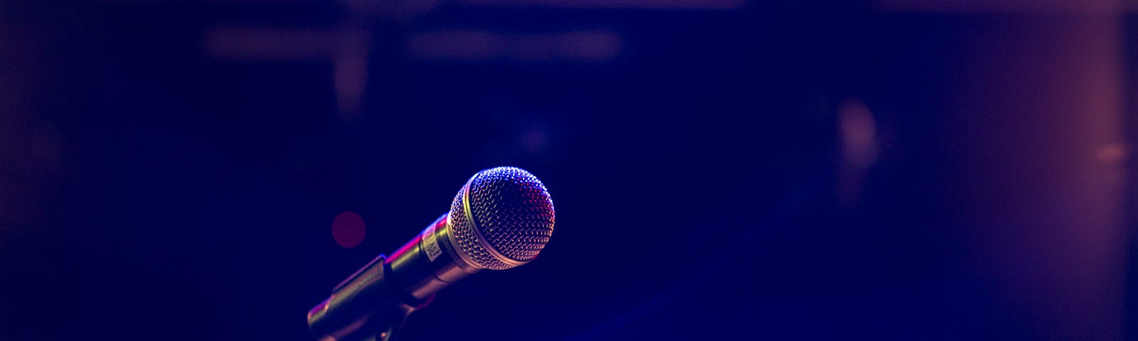 A microphone on a microphone stand in a dark club.