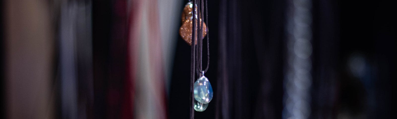 Necklaces with gemstones dangling over a table full of assorted items.