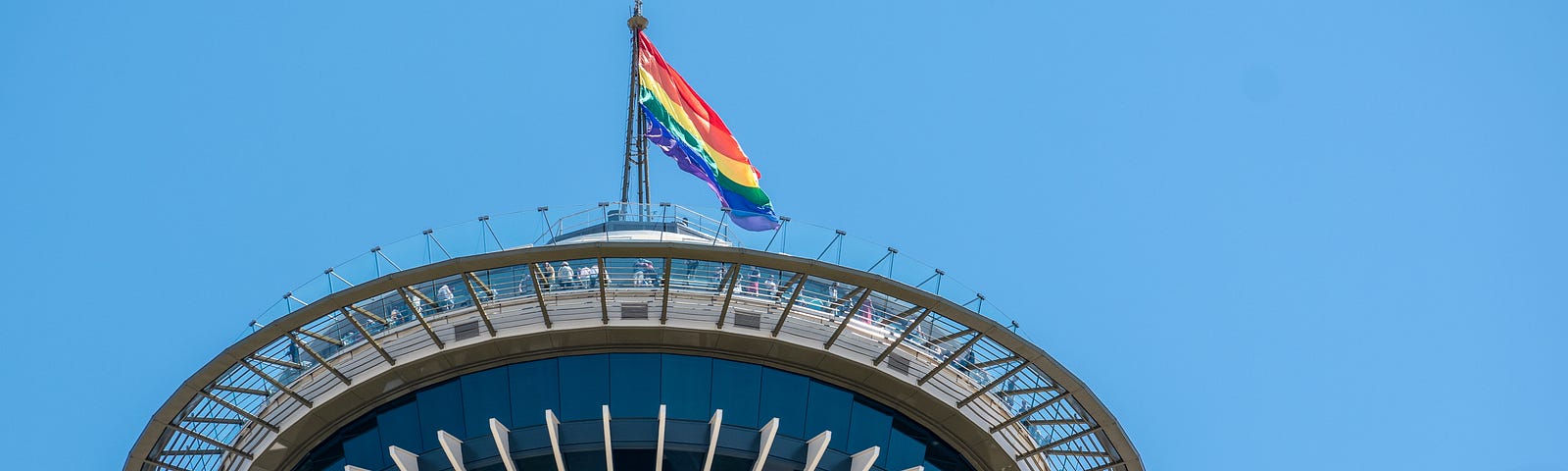 Photo of the top of the Seattle Needle with a pride flag flying on top