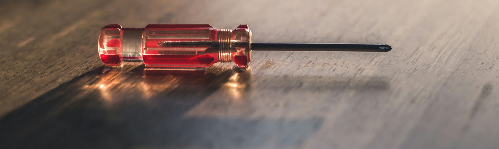 A color photograph of a single screwdriver with a wood table background.