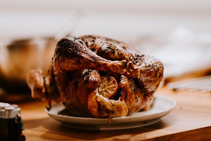 Photo of a small roasted turkey on a white platter.