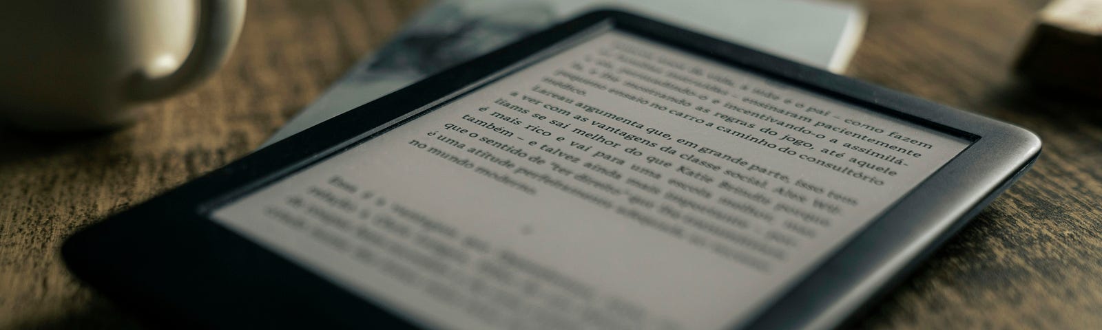 Amazon Kindle on table with coffee cup.