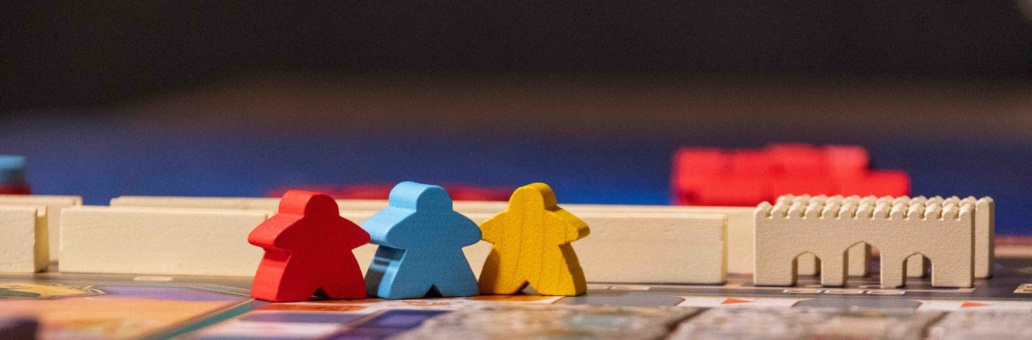 Red, blue, and yellow meeple figures in the game Merv