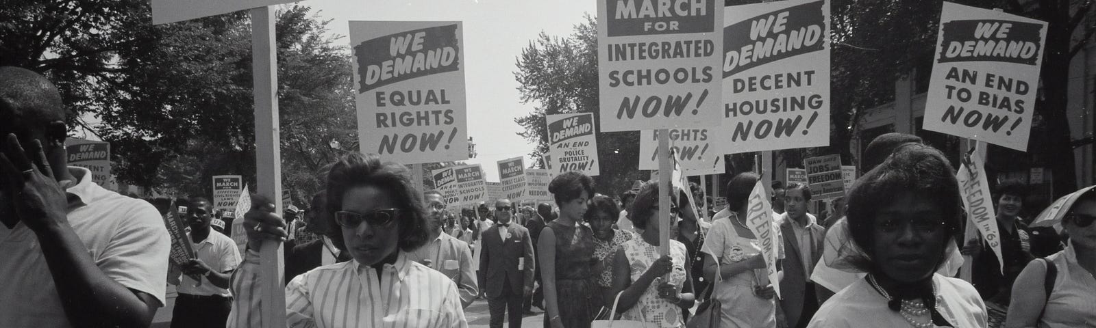 This is a black and white photo of a march against racism that seems to be from the 1950s or 1960s.