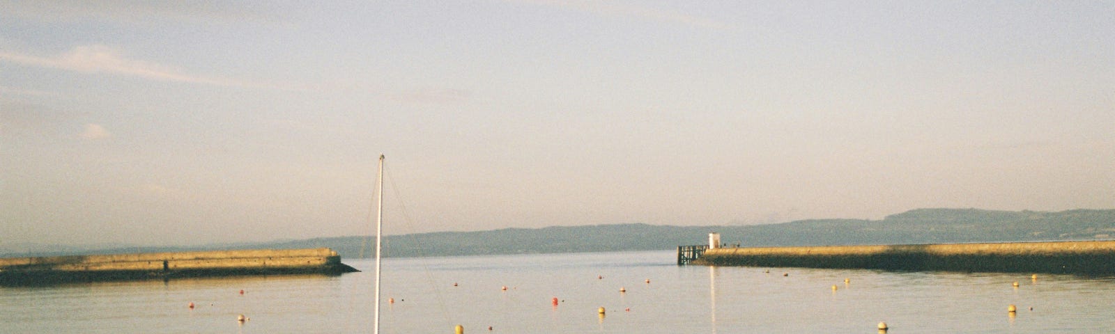 A photograph of Granton Harbour on the Firth of Forth waterfront, in the north of Edinburgh, on a beautiful clear day with a small boat in the foreground.