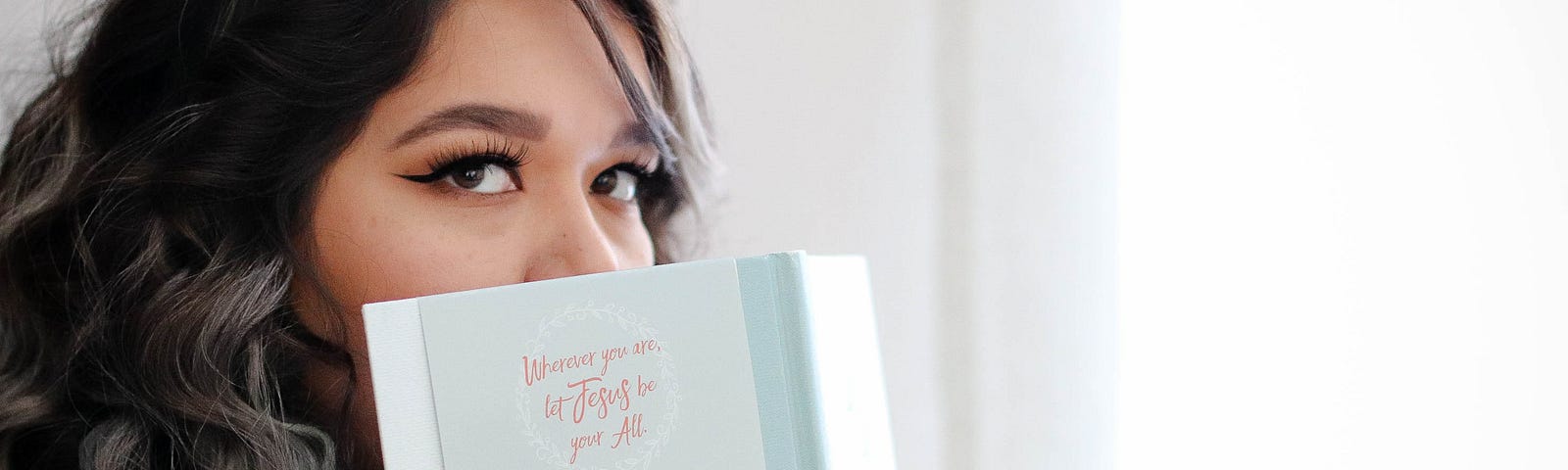 Woman peeking from behind reading book.