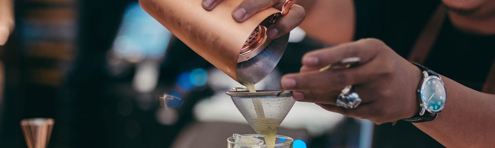 Bartender pouring a cocktail through a strainer