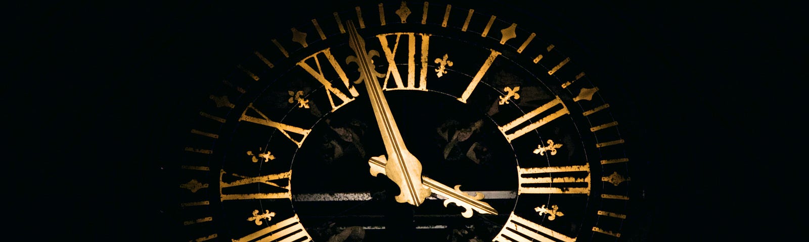 A black background behind a black clock face with gold hands and gold Roman numerals.